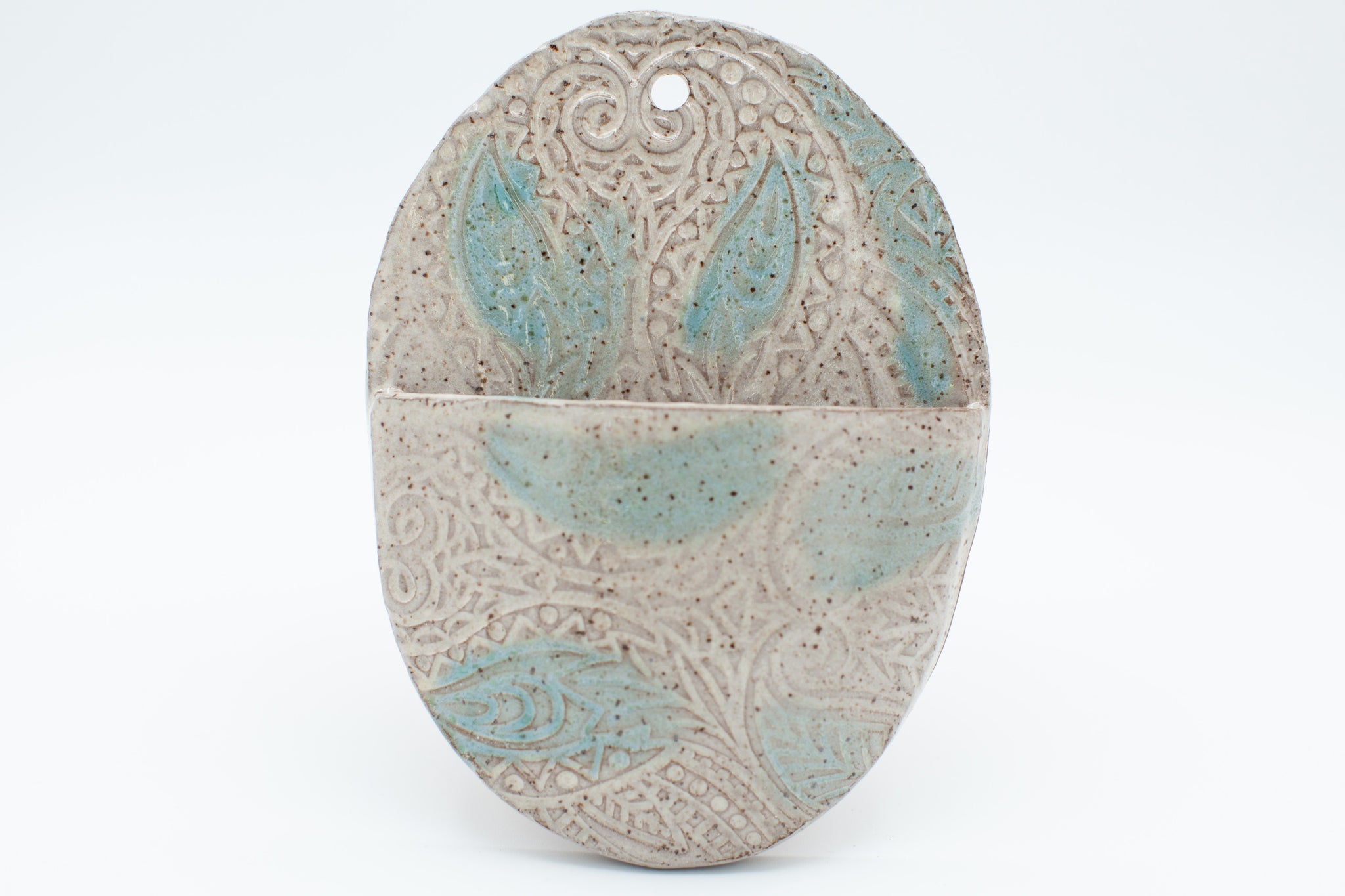 Oval wall pocket in speckled clay with spiced cream and teal glaze