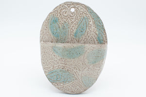 Oval wall pocket in speckled clay with spiced cream and teal glaze