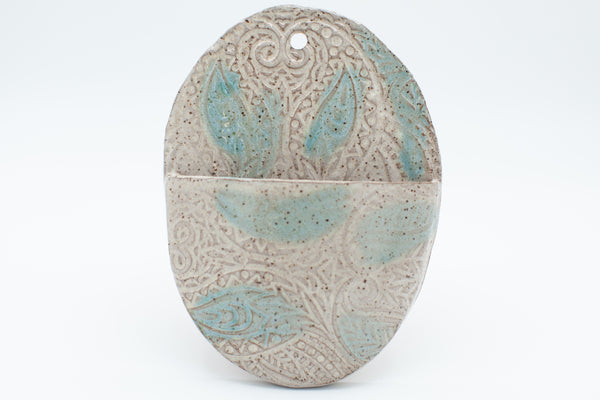 Oval wall pocket in speckled clay with spiced cream and teal glaze